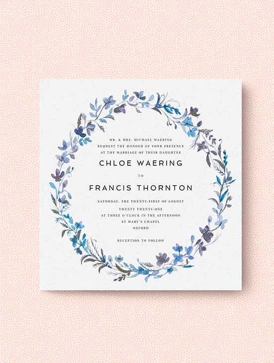 A classic wedding invitation design personalised with a blue floral wreath