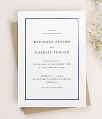 A classic wedding invitation design. The wedding invitation has a traditional navy-blue border and elegant type face.