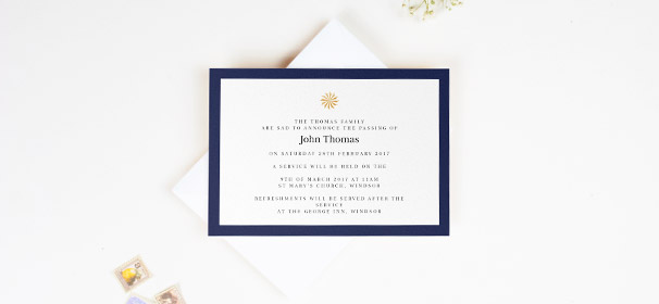 A funeral invitation card printed on a white card with a navy-blue border. There is a golden sundial in the middle. The invite is sat on an envelope.