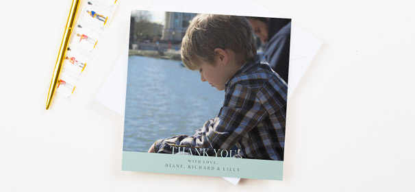 A square first holy communion thank you card design. It has a photo of a young boy, with a light blue banner at the bottom of the thank you card.