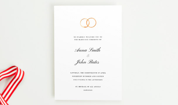 A beautiful wedding order of service booklet printed with two golden wedding rings at the top of the front cover.