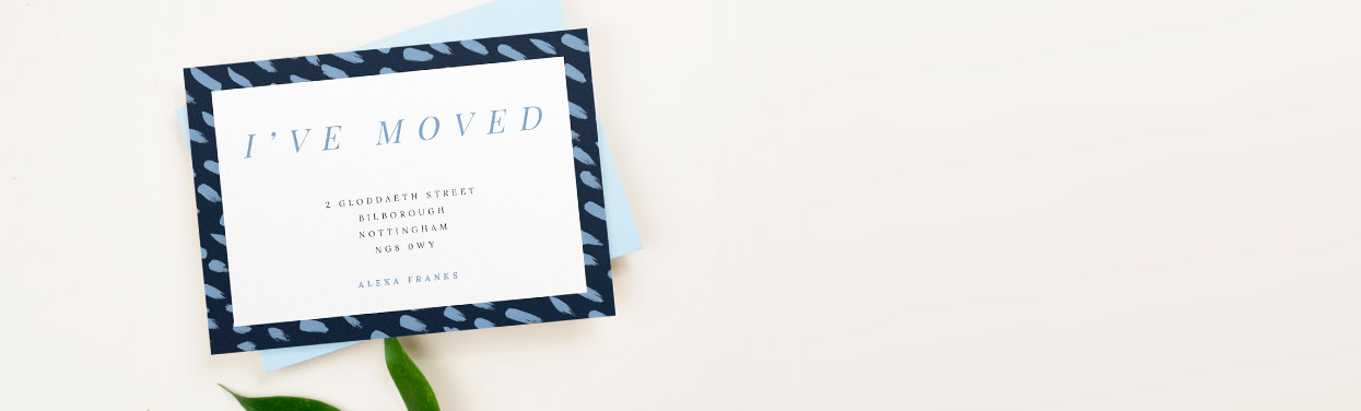 Printed change of address card with a blue envelope underneath. The moving home card is printed with a navy border and light blue paint strokes.
