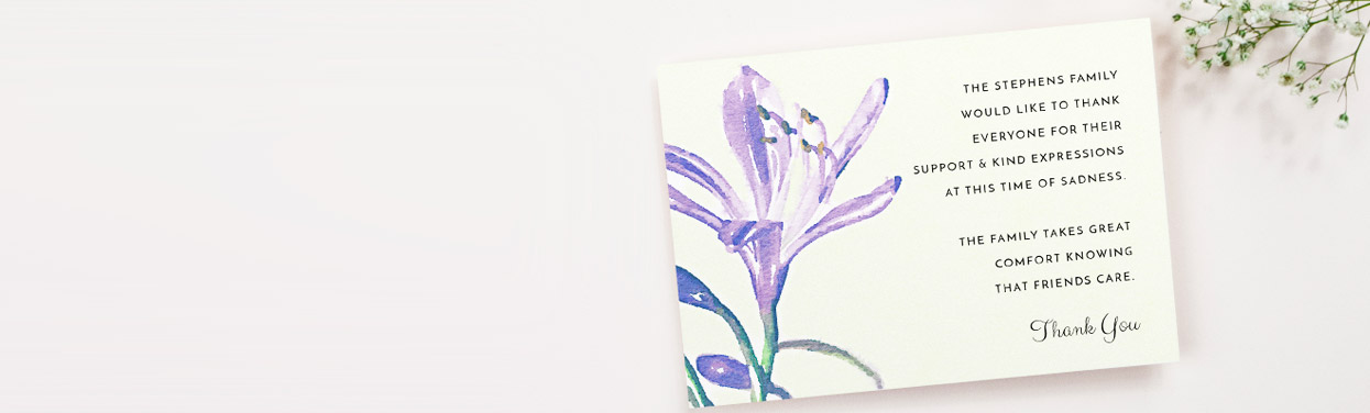 A printed funeral announcement card with a purple, watercolour flower design. The card has a personalised message on the right-hand side.