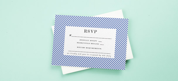 A wedding RSVP card sat on a little envelope. The response card is printed with a modern, blue and white border.