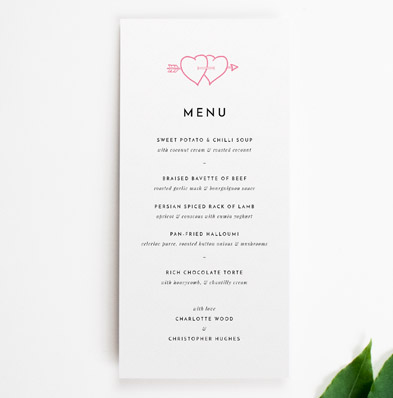 A simple wedding menu design. It is a tall and thin wedding menu card with two pink hearts at the top. It lists the wedding meal courses.