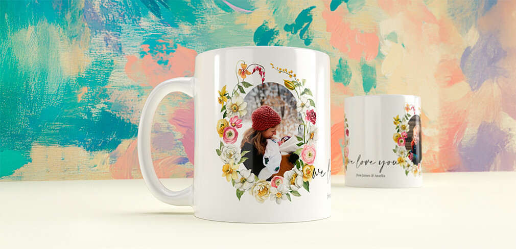 Two personalised photo mugs with floral wreaths and family imagery on pastel backdrop