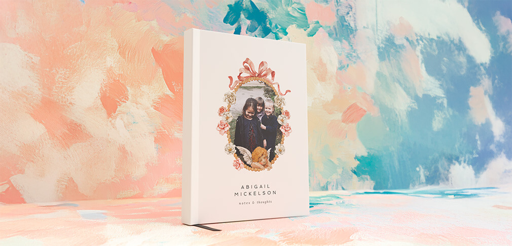 Custom photo notebook with pink floral frame and ribbon design on soft pastel background