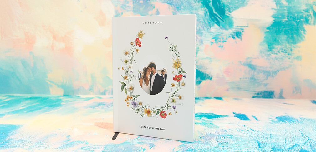 Personalised wedding notebook with floral design and couple’s photo on pastel background