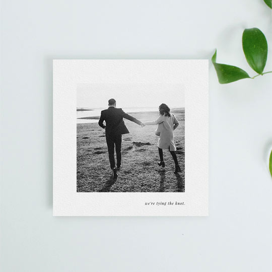 A simple and classic wedding save the date card with photos. It has a medium sized photo in black and white in the centre of the card. Underneath the save the date photo, the words “we’re tying the know” are printed in black.