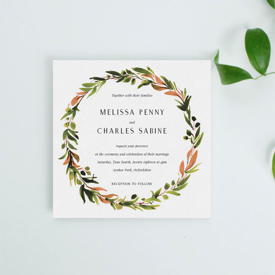 A square wedding invitation with a classic floral wreath. The invitation’s wreath is painted with shades of greens and oranges. The font is classic and simple.