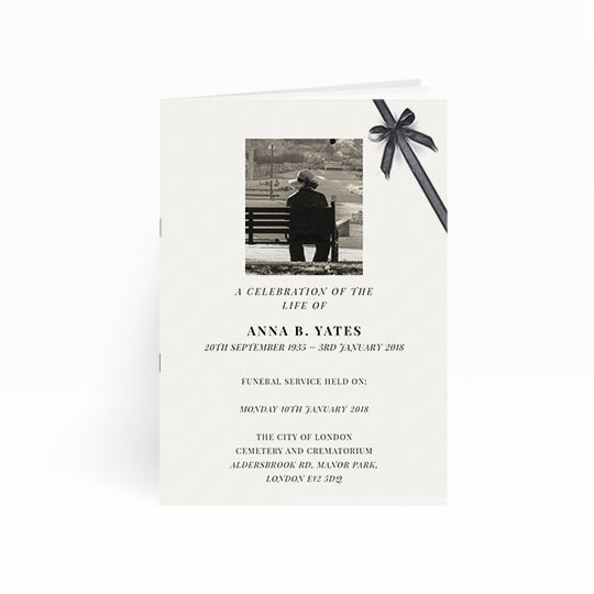 An elegant, multi-paged order of service booklet for a funeral. The program is predominantly white, with a painted, black ribbon running across the top-right hand corner. There is a black and white photo on the front cover.