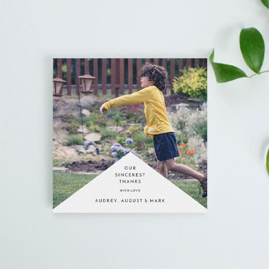 A modern first holy communion thank you card design with a large photo of a young boy, and a triangular white segment underneath. The card’s white section has a personalised message of thanks.
