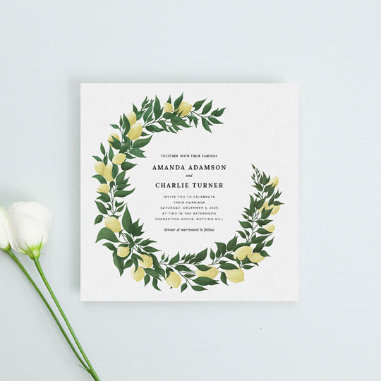 A rustic wedding invitation design made from a two-third wreath of lemons and leaves. The wreath has been hand-painted and frames some central text detailing an upcoming marriage ceremony.