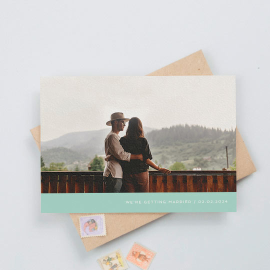 A simple photo wedding save the date card with a full-width colour photo. It has a mint green bottom with white text reading “we’re getting married”