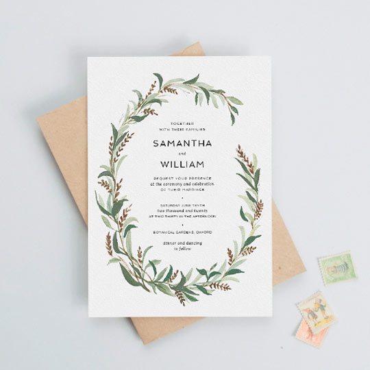 A vintage, winter-wedding invitation. The wedding invitation has a painted two-thirds wreath made up of muted green and brown leaves.