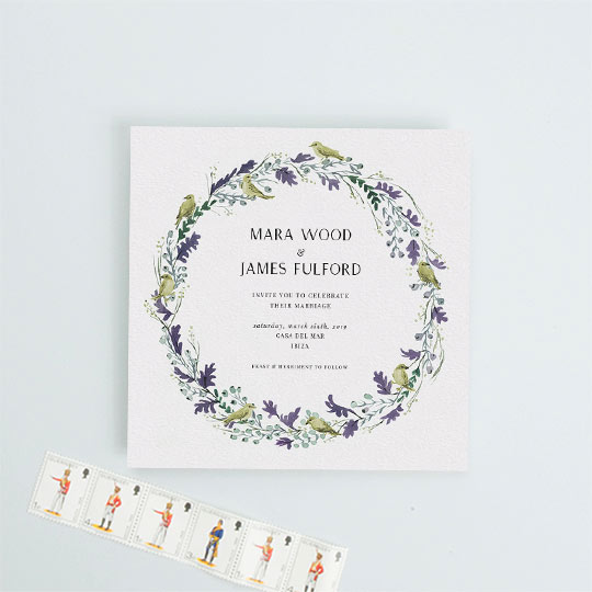 A square wedding invitation design made up of a yellow and purple wreath of oak leaves and songbirds.