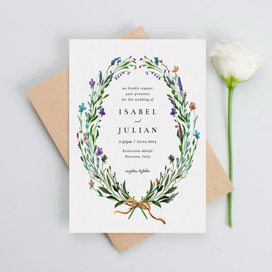 A rustic floral wedding invitation made of painted wildflowers. The wreath is very rustic, and frames centralised black text.