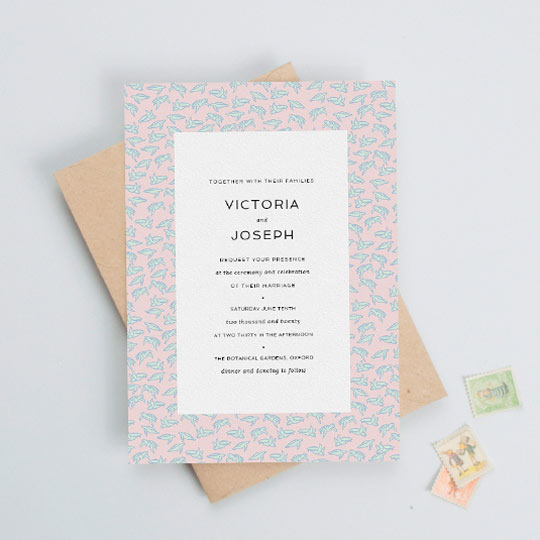 A quirky and unusual wedding invitation with a border of tiny blue turtles on a light pink background. The wedding invitation text in the middle is very elegant and printed in black ink.