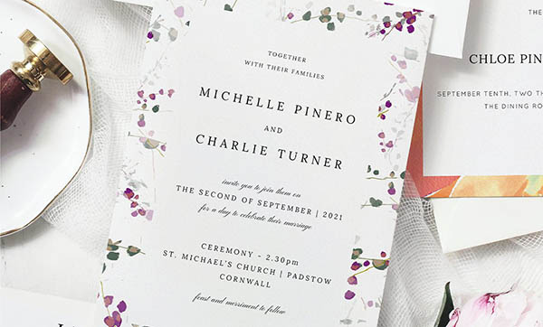 A beautiful floral wedding stationery design, sat on a table with other pieces of printed stationery.