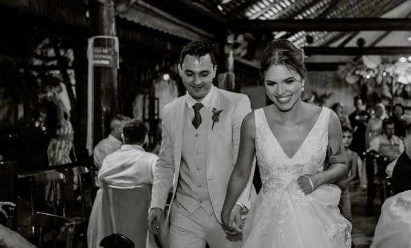 A black and white photo of a couple walking away from their marriage ceremony.