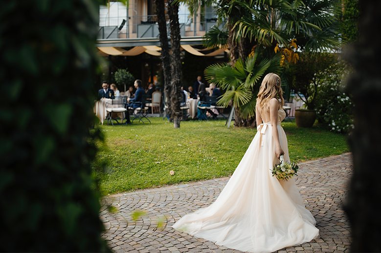 Bride in a garden, holding a bouquet of flowers.