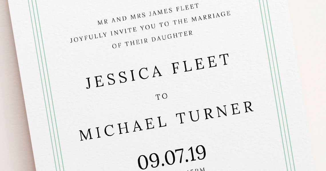 Close-up of a detailed green wedding invitation card with serif text and floral design. Close-up of a detailed green wedding invitation card with serif text and floral design.