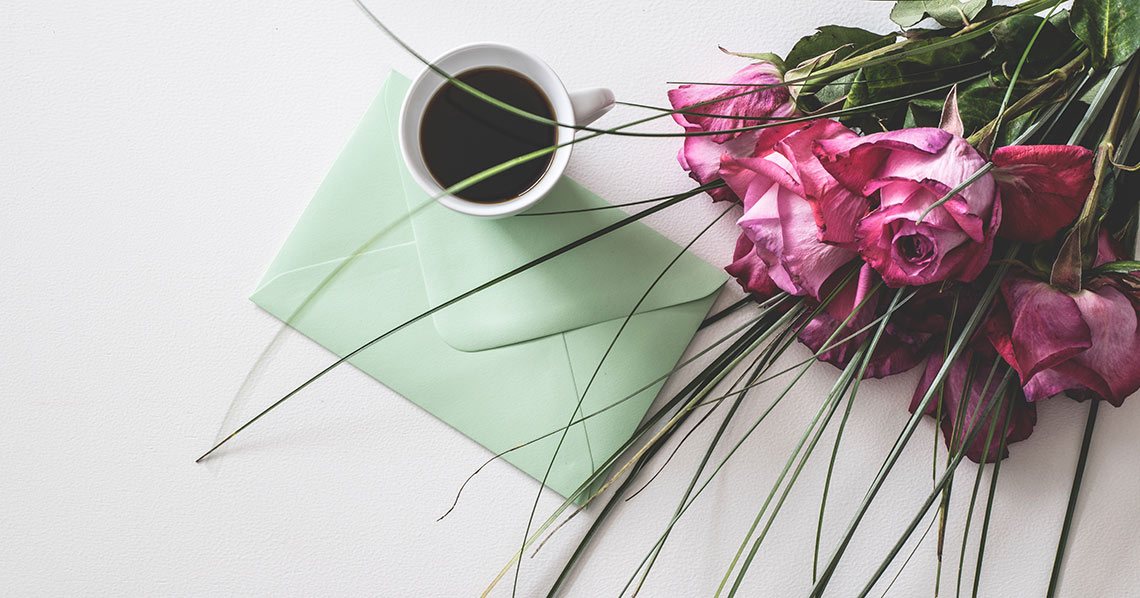 A handwritten thank you card in a blue envelope, by a bunch of wedding flowers.