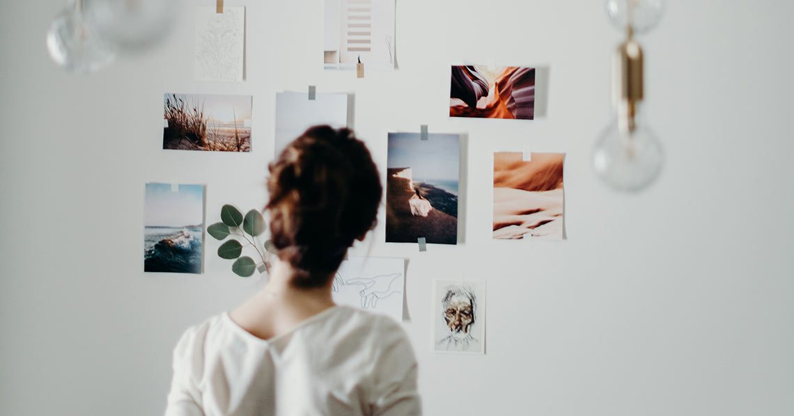 A photographer looking at some photos taped to her studio wall.