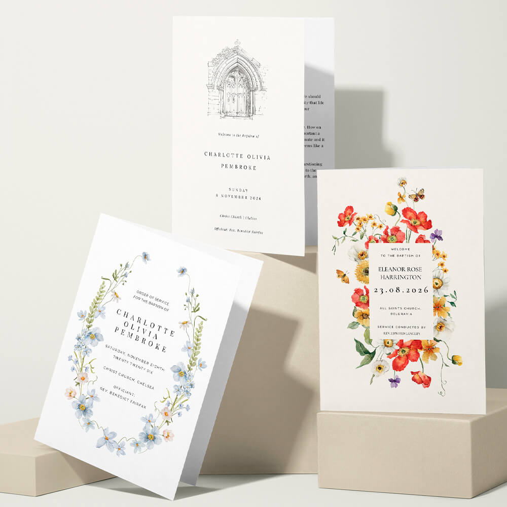 Three christening order of service booklets with floral and illustrated church arch designs, arranged on neutral blocks with soft shadows