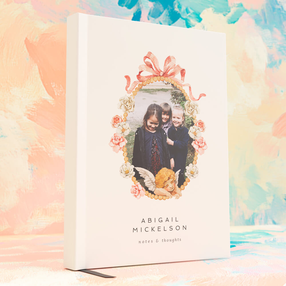 Children’s personalised notebook with a photo of three smiling kids framed by vintage floral and ribbon artwork, set against a pastel background