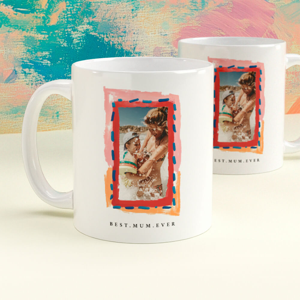 Personalised white photo mug with “Best Mum Ever” caption and a colourful frame surrounding an image of a mother and baby on the beach