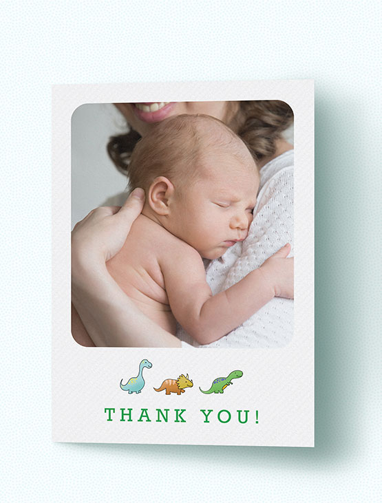 A folded baby thank you card with photo and dinosaurs